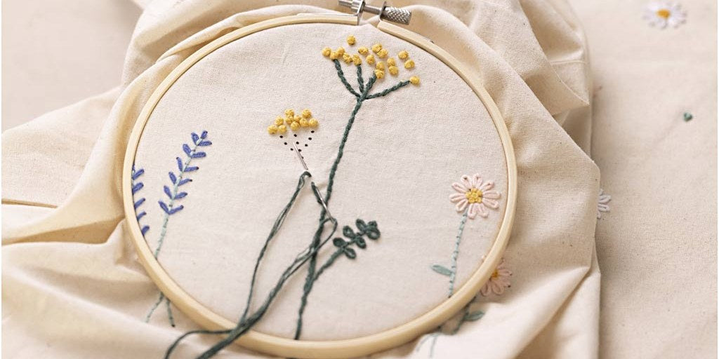 Broderiramme med broderede blomster på et stofnet